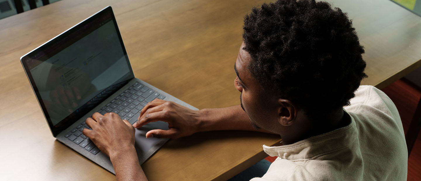 A young man, seated, working on a laptop