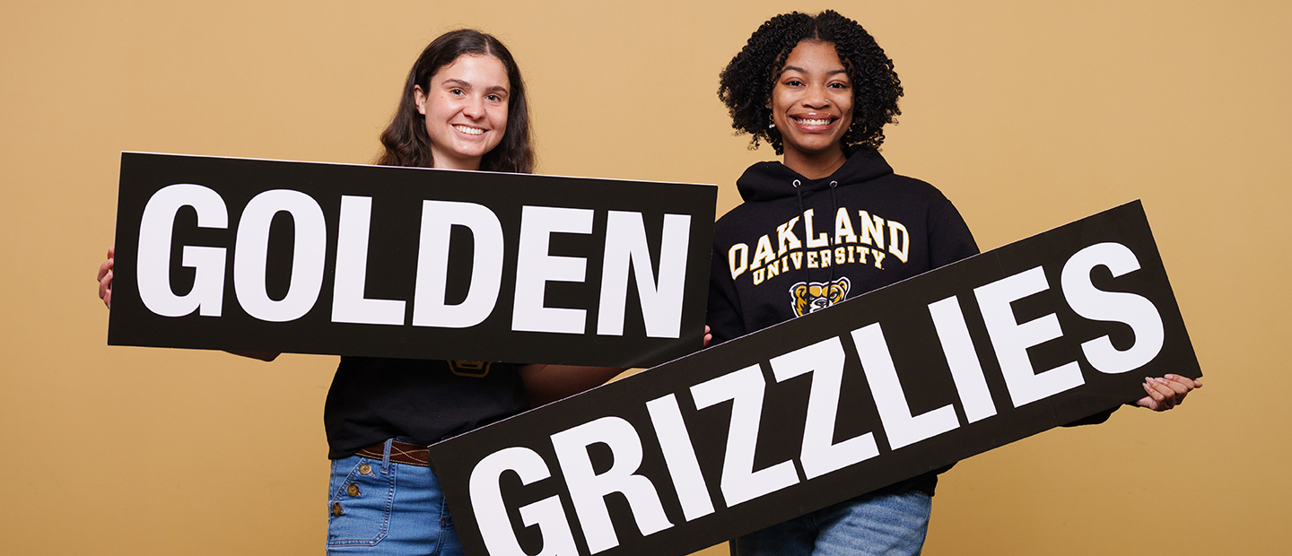 Two students holding a sign that says 