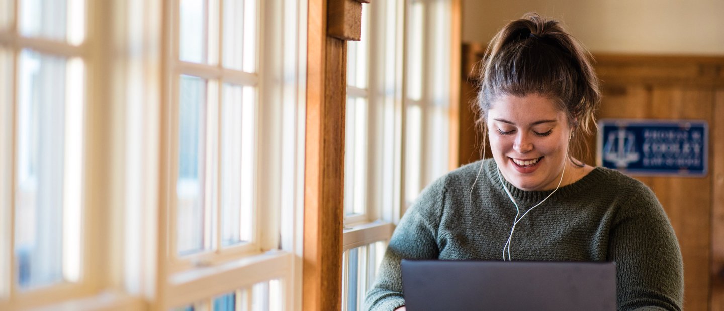 woman wearing headphones looking down at an open laptop