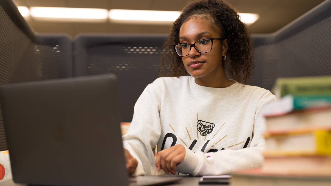 student sitting with laptop and books