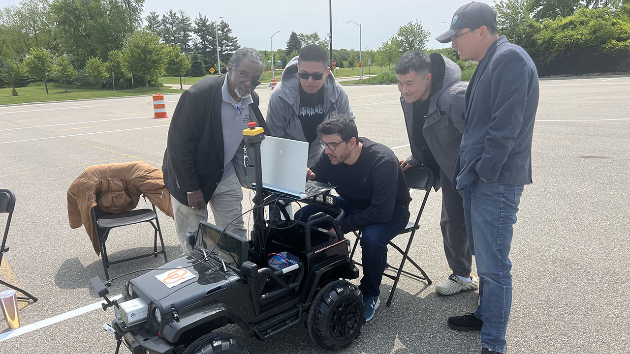 Competitors at the 32nd Annual Intelligent Ground Vehicle Competition looking at vehicle