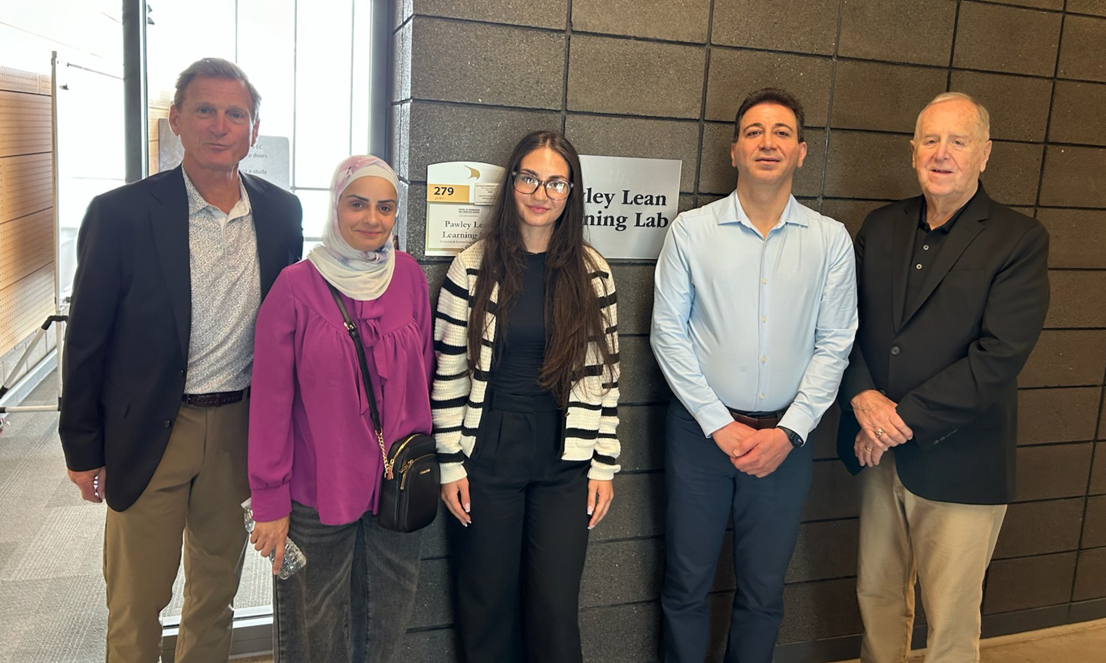 Five people standing in a row, smiling