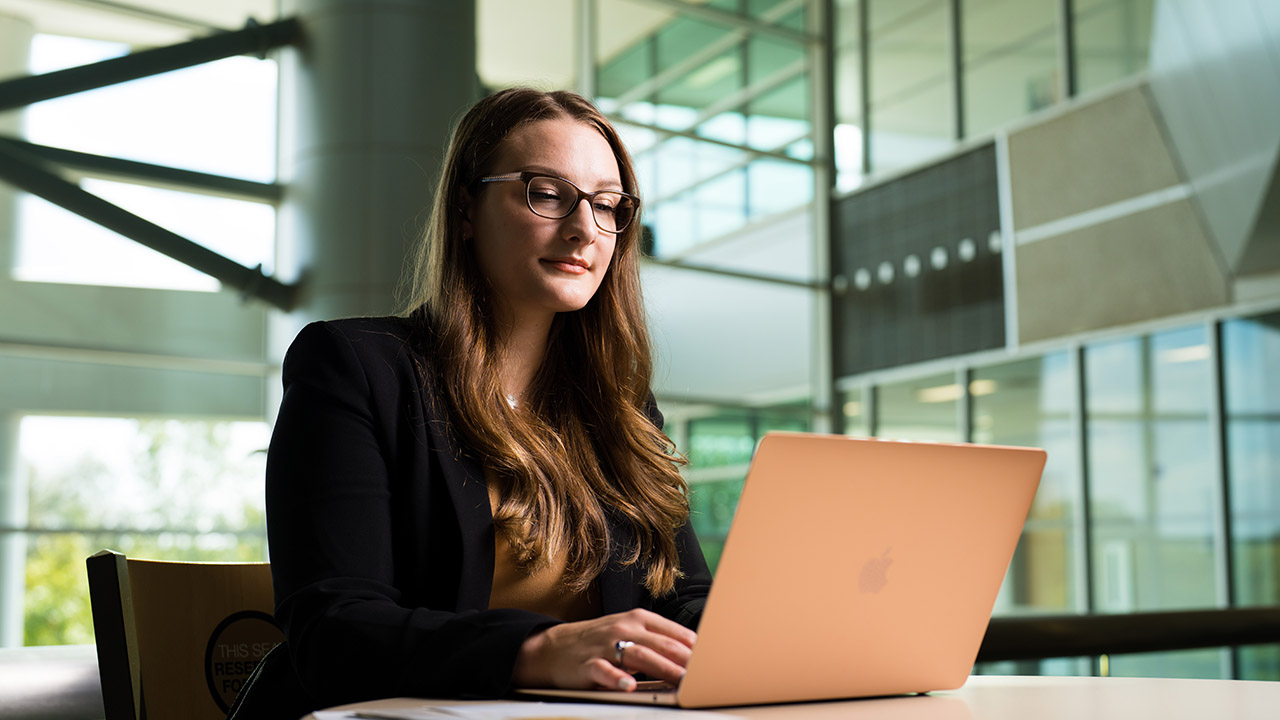 Female SBA student in glasses sitting at laptop