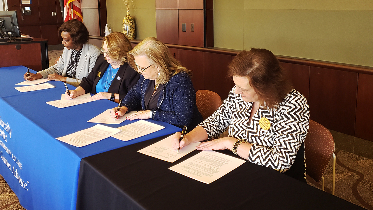 Four people signing papers at a table.