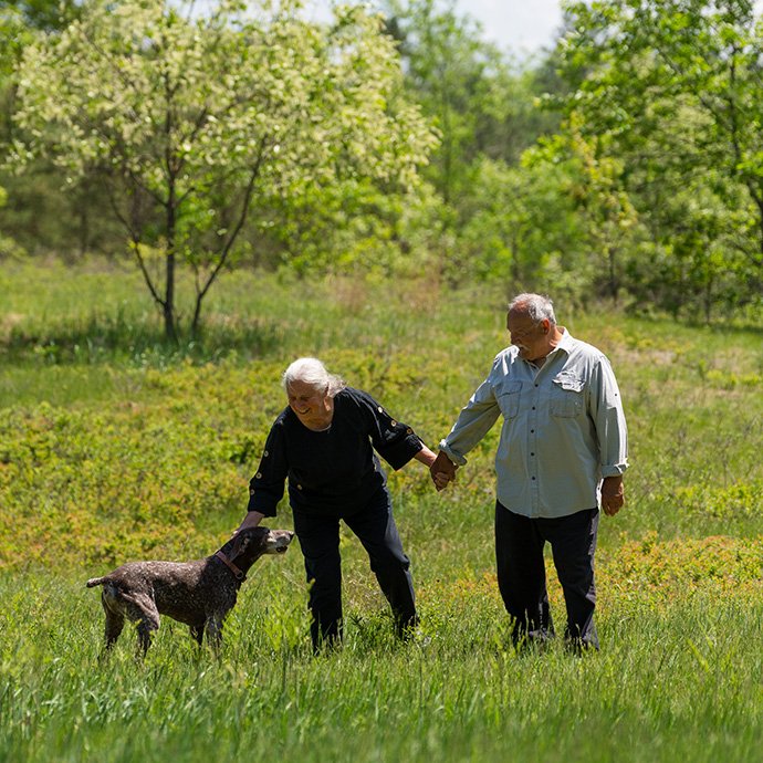 A husband and wife in the field with their dog