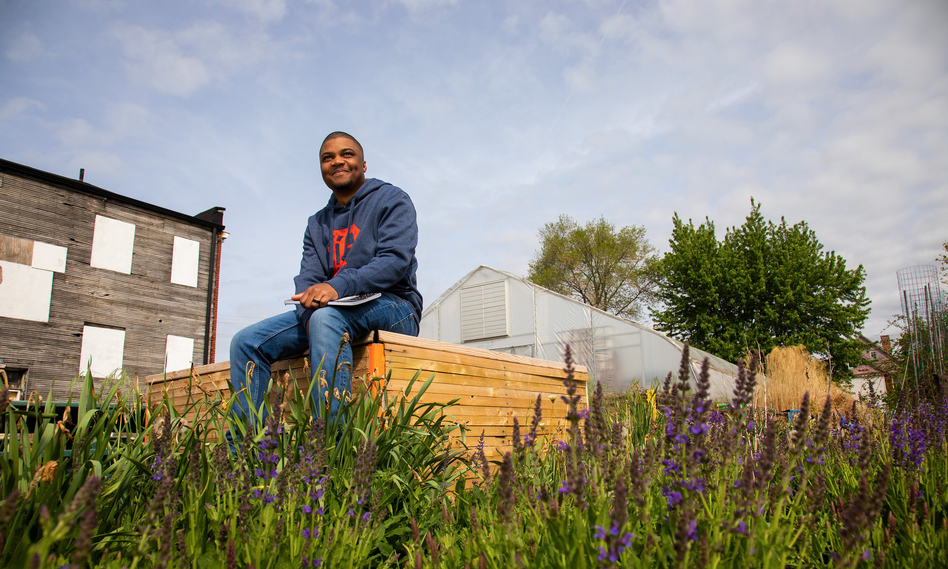 A man sitting on a planter box with a notebook