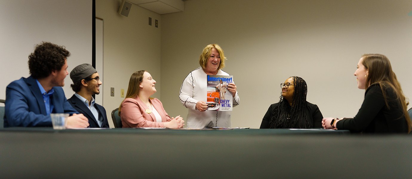 A woman presenting a magazine to a group of people