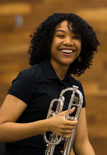 Alexis Dill smiling and holding a trumpet