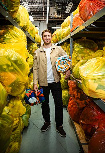 A person standing in an aisle, holding and surrounded by blankets