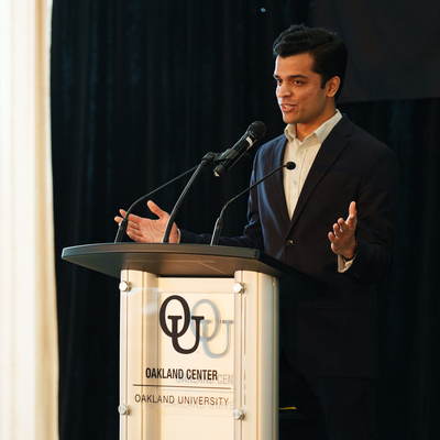 Aadeesh Diman speaking at a podium.
