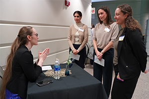 An image of three students talking to an OUWB alumnus