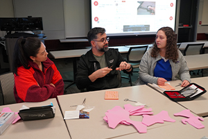 Two students and a Corewell physician sitting and talking at a table