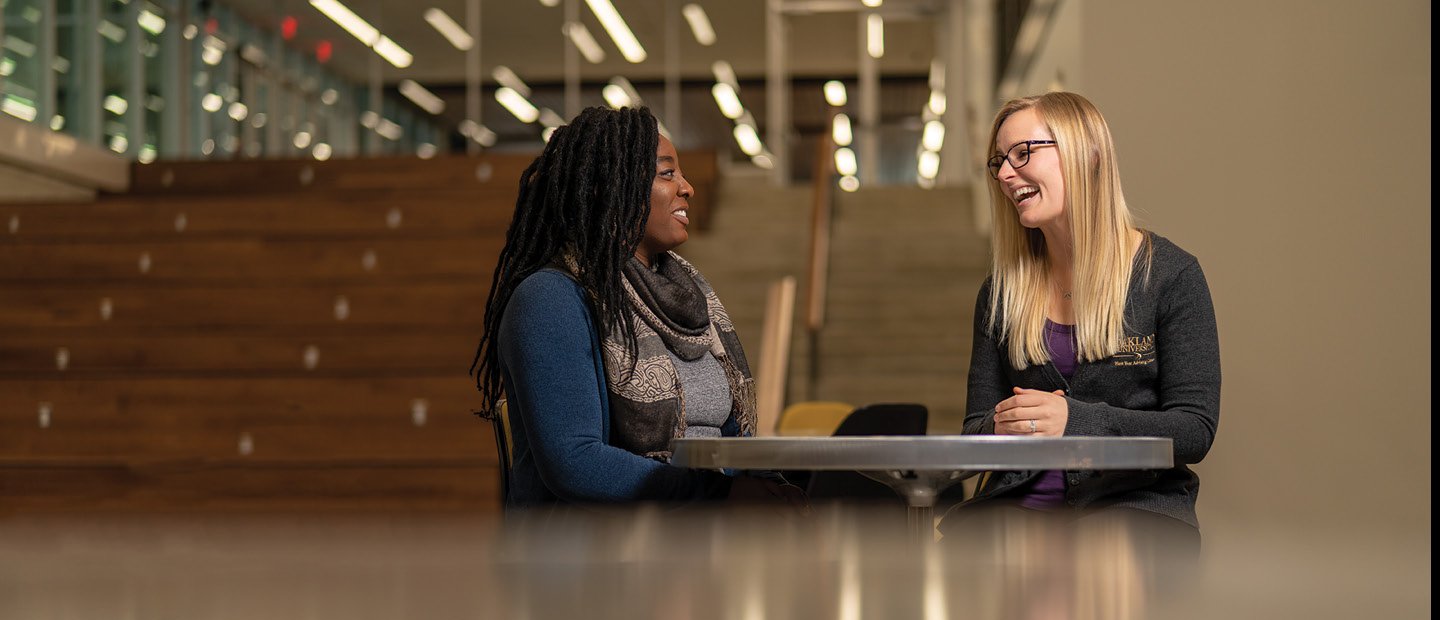 Two women seated at a table smiling and talking