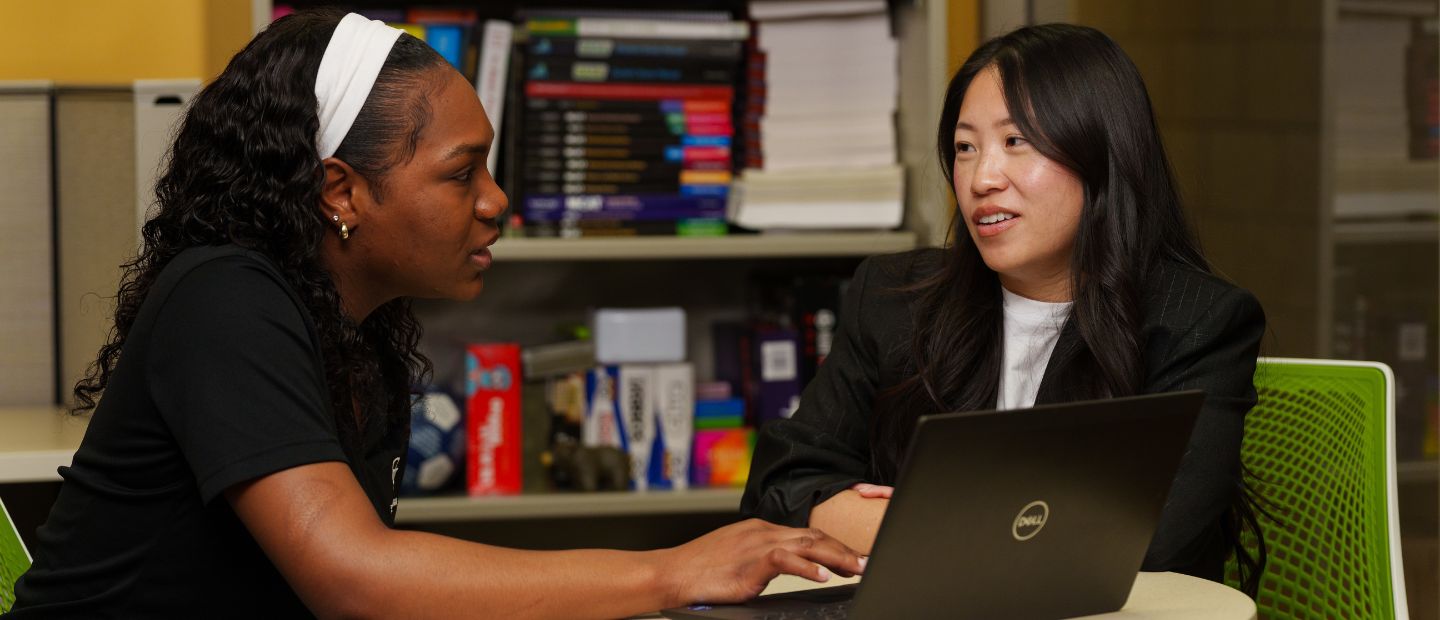 An adviser and student talking at a table.