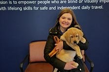 Annie Fuelle sitting in a chair holding a golden retriever puppy.