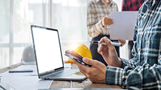 A person seated at a table with an open laptop.
