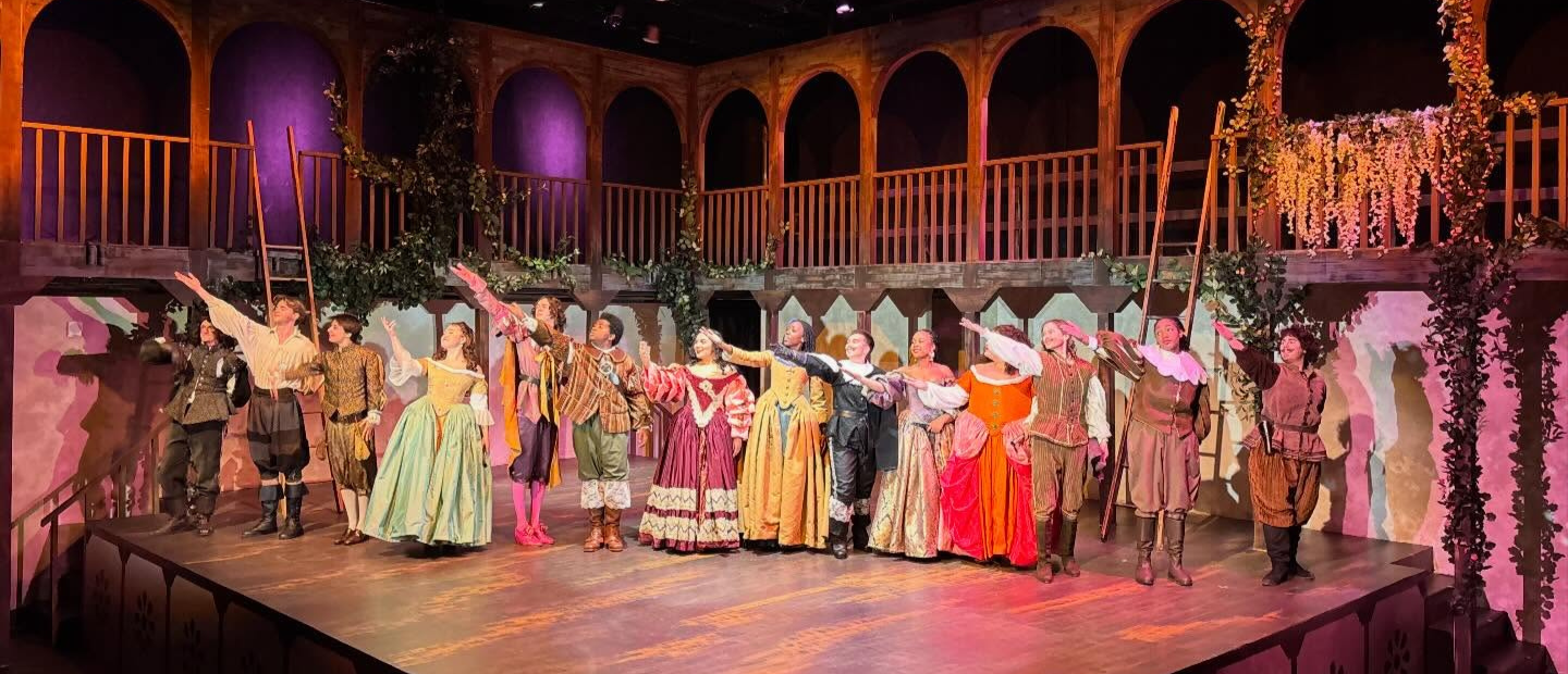 The cast of a play gesturing towards the audience