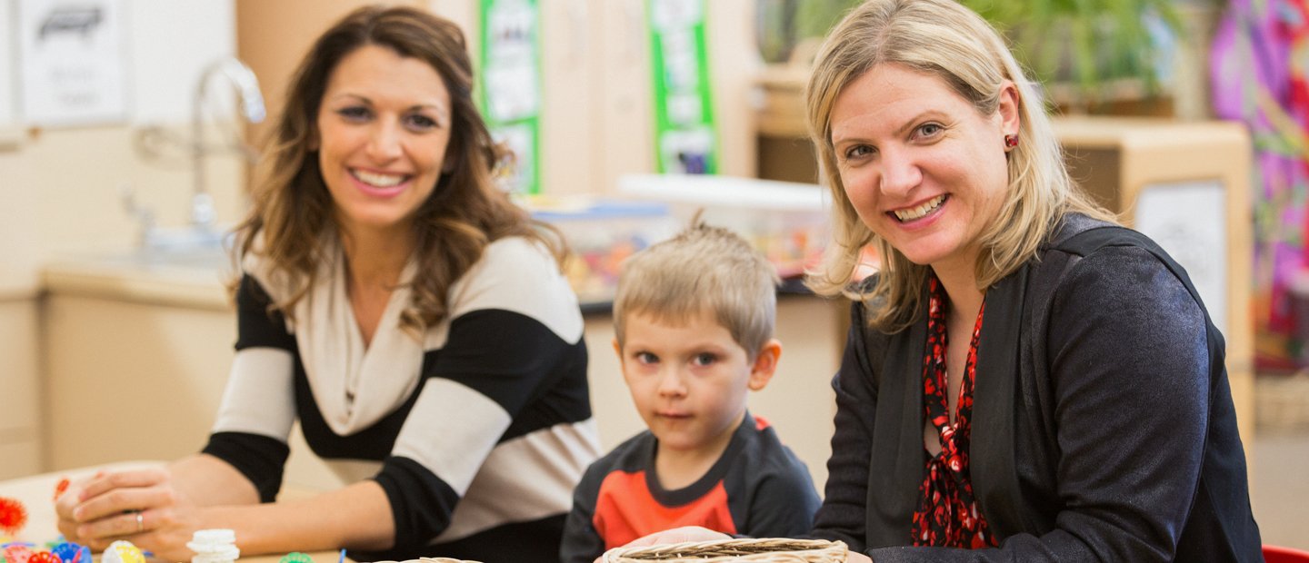 Two women sitting next to a child