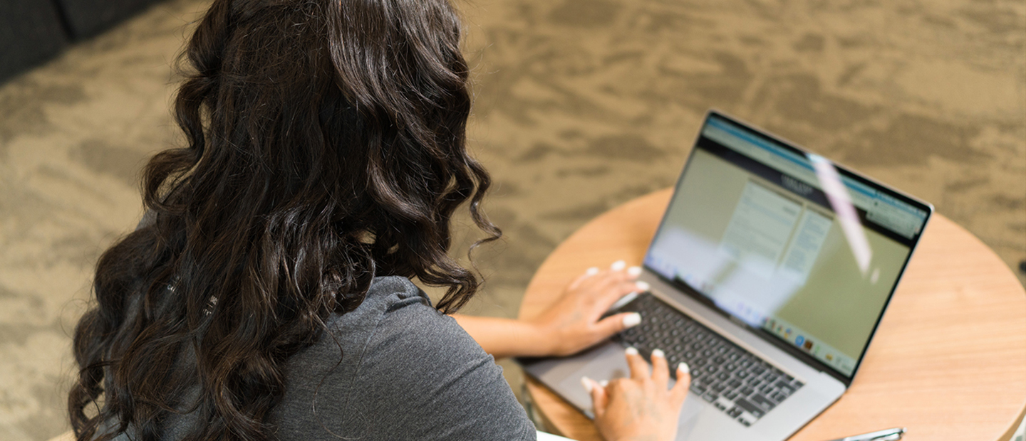 A woman using an Oakland University website on a laptop